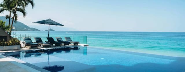 Infinity pool with lounge chairs overlooking the Pacific